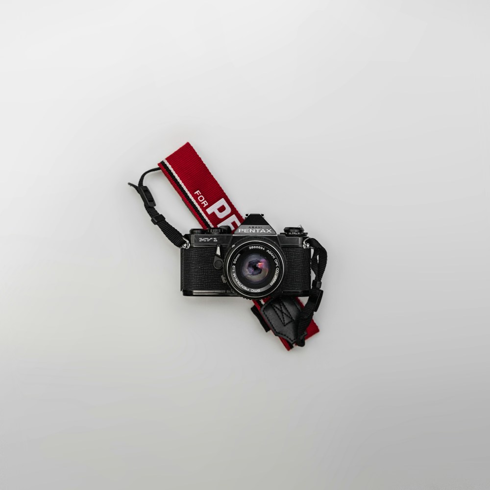 A black Pentax camera photographed against a pale background